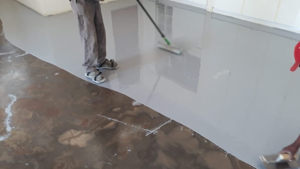 APR Waterproofing applying epoxy coating on a house garage floor.